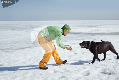 Image of Young adult man outdoors with his dog having fun in winter lands