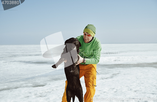 Image of Young adult man outdoors with his dog having fun in winter lands