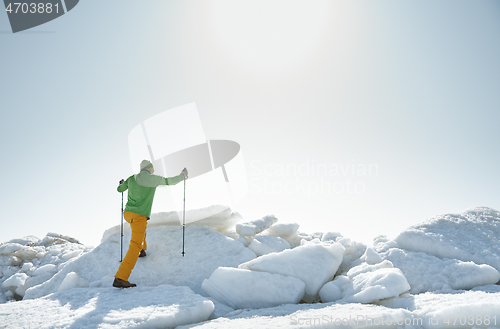 Image of Young adult man outdoors with walking sticks exploring icy lands