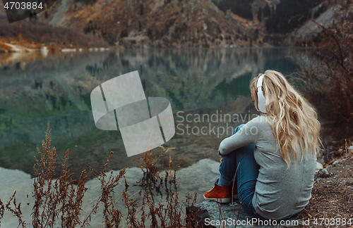 Image of Woman wearing wireless headshot at the mountain lake