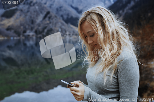 Image of Woman using smartphone at the lake