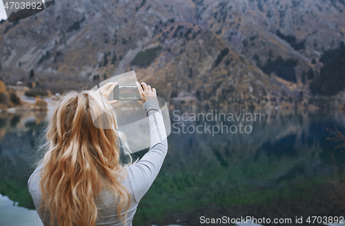 Image of Woman making mobile photo at the mountain lake