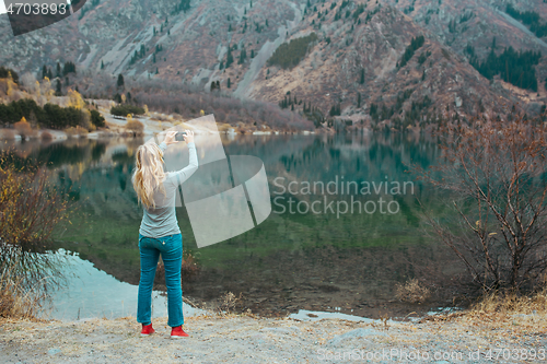 Image of Woman making mobile photo at the mountain lake