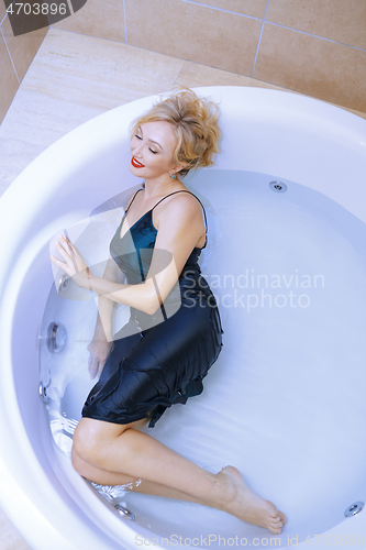 Image of Woman wearing slip dress relaxing in the bath