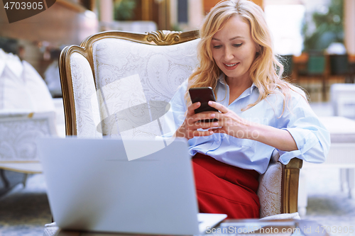 Image of Businesswoman using smartphone in the modern bank lobby