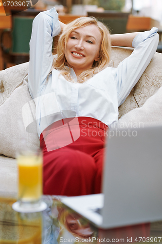 Image of Woman relaxing in the hotel lobby and blogging via laptop