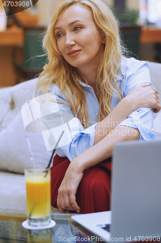 Image of Woman relaxing at the hotel lobby and blogging via laptop