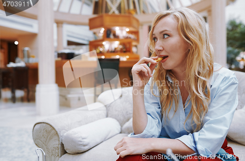 Image of Woman enjoying snack and sitting at the hotel lobby