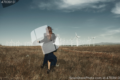 Image of Woman with long tousled hair next to the wind turbine with the w