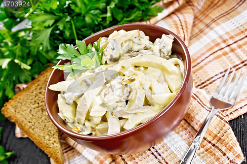 Image of Salad with squid and champignons in bowl on napkin