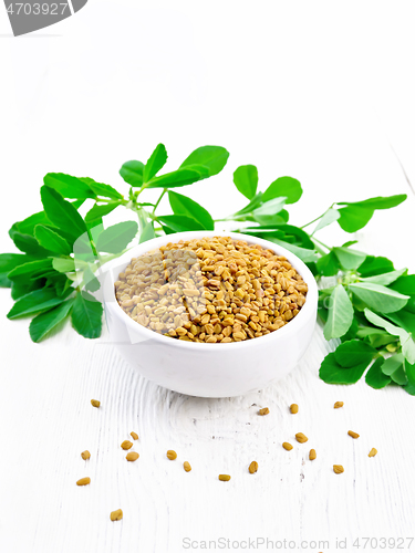 Image of Fenugreek with green leaves in bowl on light wooden board