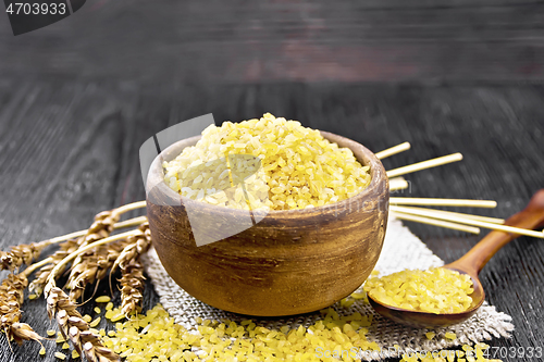 Image of Bulgur in bowl on dark wooden board