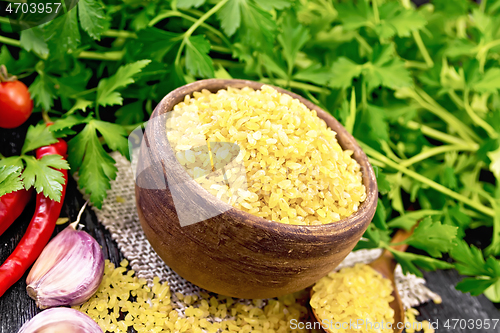 Image of Bulgur in bowl with vegetables on dark wooden board