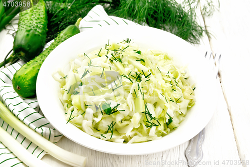 Image of Salad of cabbage with cucumber in plate on board