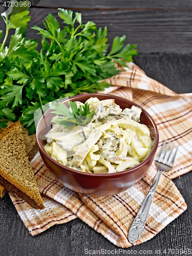 Image of Salad with squid and champignons in bowl on wooden board