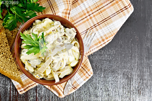 Image of Salad with squid and champignons in bowl on board top