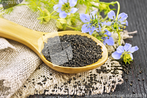 Image of Seeds of black cumin in spoon on dark board