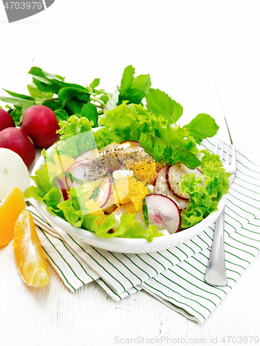 Image of Salad of radish and orange with mint on light wooden board