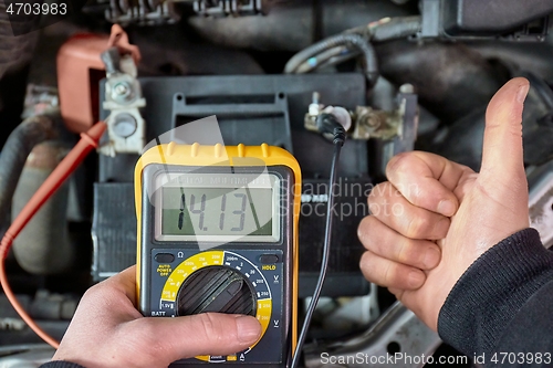 Image of Checking car battery and alternator voltage with running engine