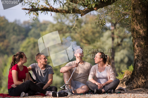 Image of friends smoking hookah on the river bank