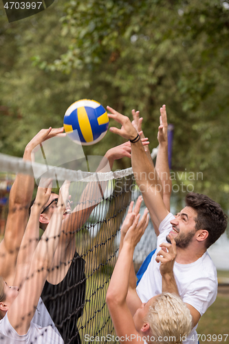 Image of group of young friends playing Beach volleyball