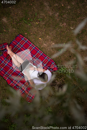 Image of top view of man using a laptop computer under the tree