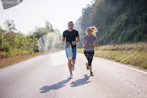 Image of young couple jogging along a country road