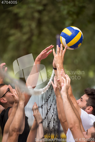 Image of group of young friends playing Beach volleyball