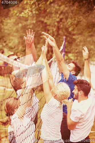 Image of group of young friends playing Beach volleyball