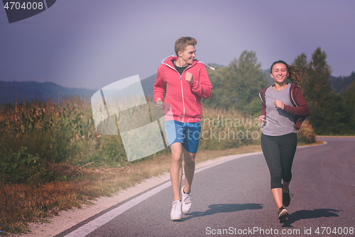 Image of young couple jogging along a country road