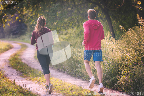 Image of young couple jogging along a country road