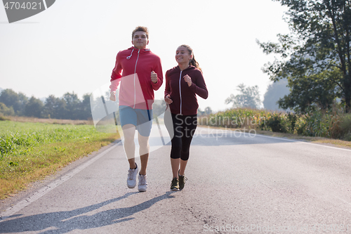 Image of young couple jogging along a country road