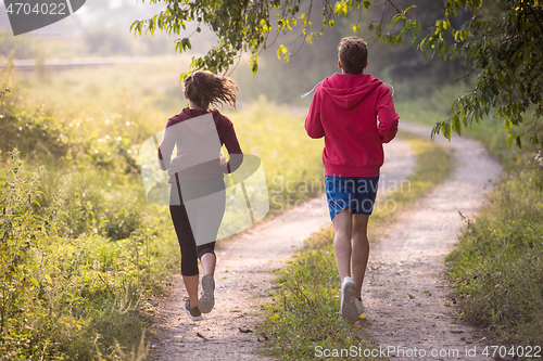 Image of young couple jogging along a country road