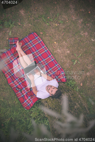 Image of top view of man using a laptop computer under the tree