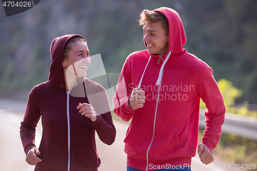 Image of young couple jogging along a country road
