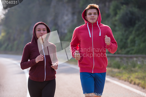 Image of young couple jogging along a country road