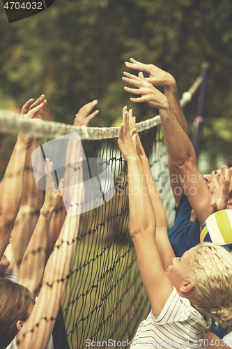 Image of group of young friends playing Beach volleyball