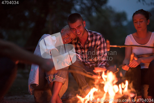 Image of young friends relaxing around campfire