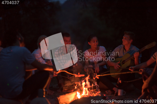 Image of young friends relaxing around campfire