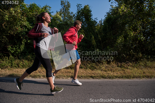 Image of young couple jogging along a country road