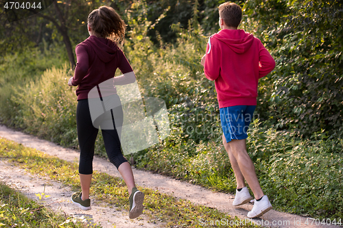 Image of young couple jogging along a country road