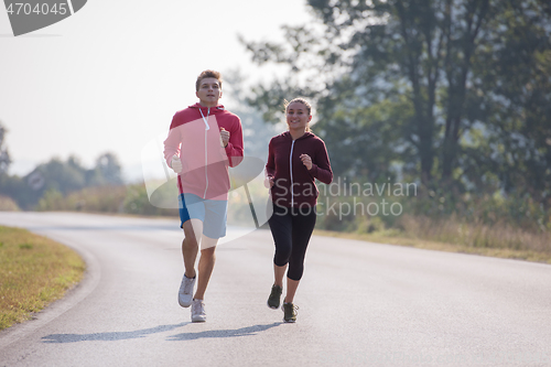 Image of young couple jogging along a country road