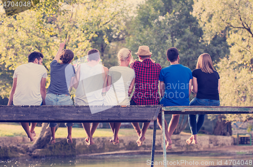 Image of rear view of friends enjoying watermelon while sitting on the wo