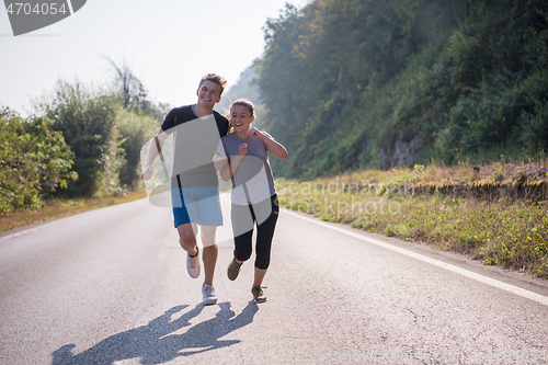 Image of young couple jogging along a country road