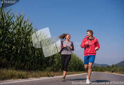 Image of young couple jogging along a country road