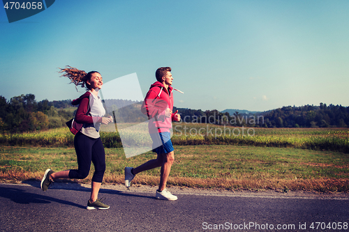 Image of young couple jogging along a country road