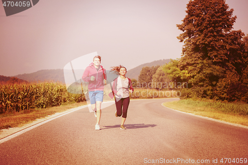 Image of young couple jogging along a country road