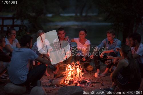 Image of young friends relaxing around campfire