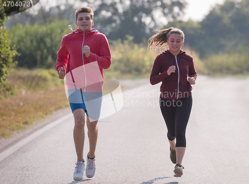 Image of young couple jogging along a country road