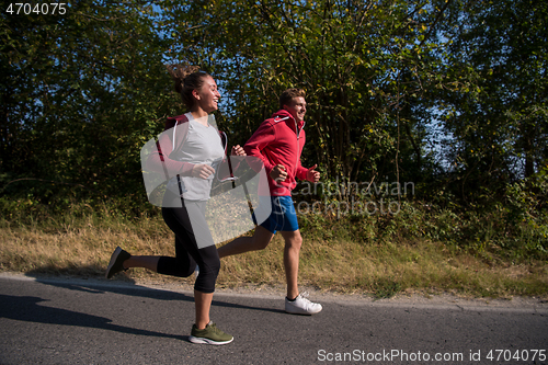 Image of young couple jogging along a country road
